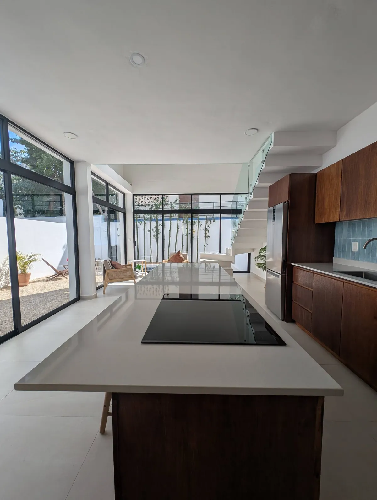 Modern kitchen with a white island, induction cooktop, and walnut cabinets