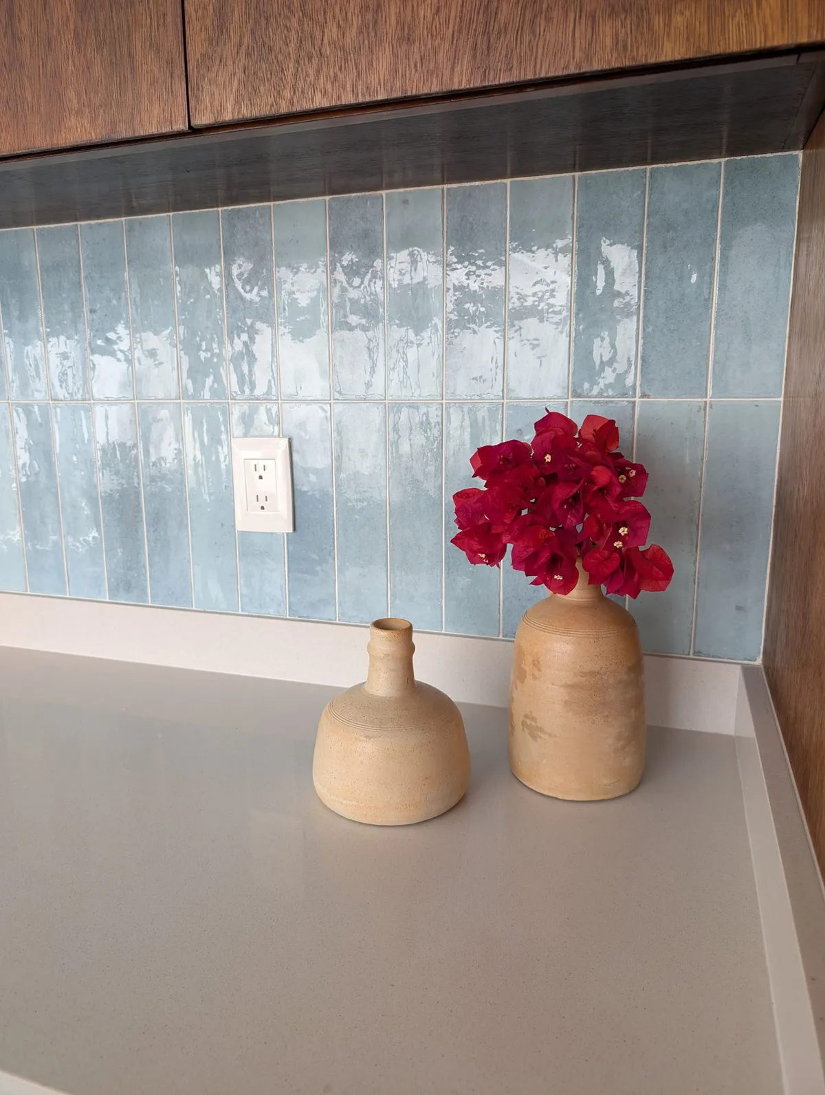 Kitchen counter with a blue tile backsplash and ceramic vases
