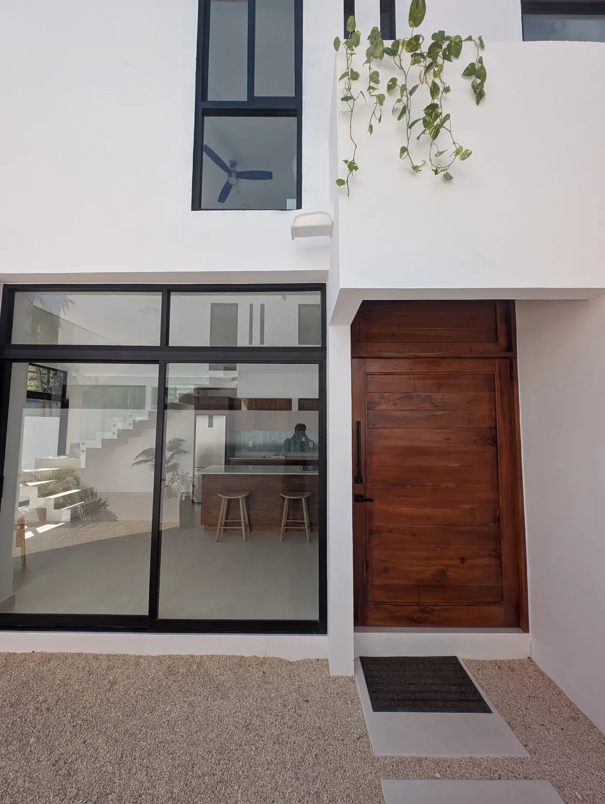 Front entrance with a wooden door and glass doors into the open-plan living area