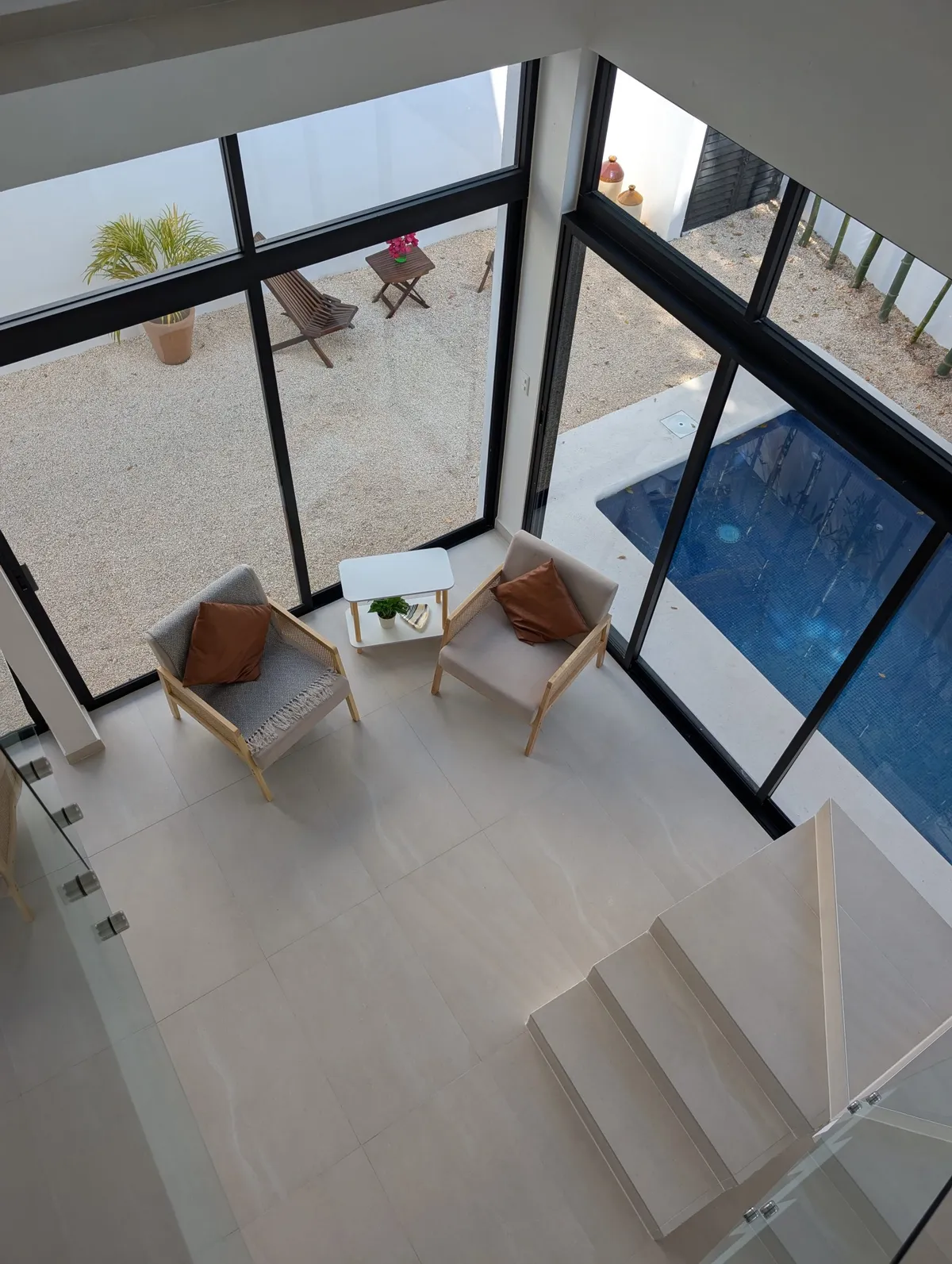Double-height living room with glass walls looking onto the pool